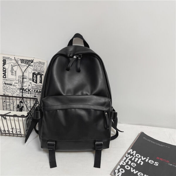 Bolso mochila mujer en cuero negro para viaje, colocado sobre un escritorio blanco y contra una pared gris